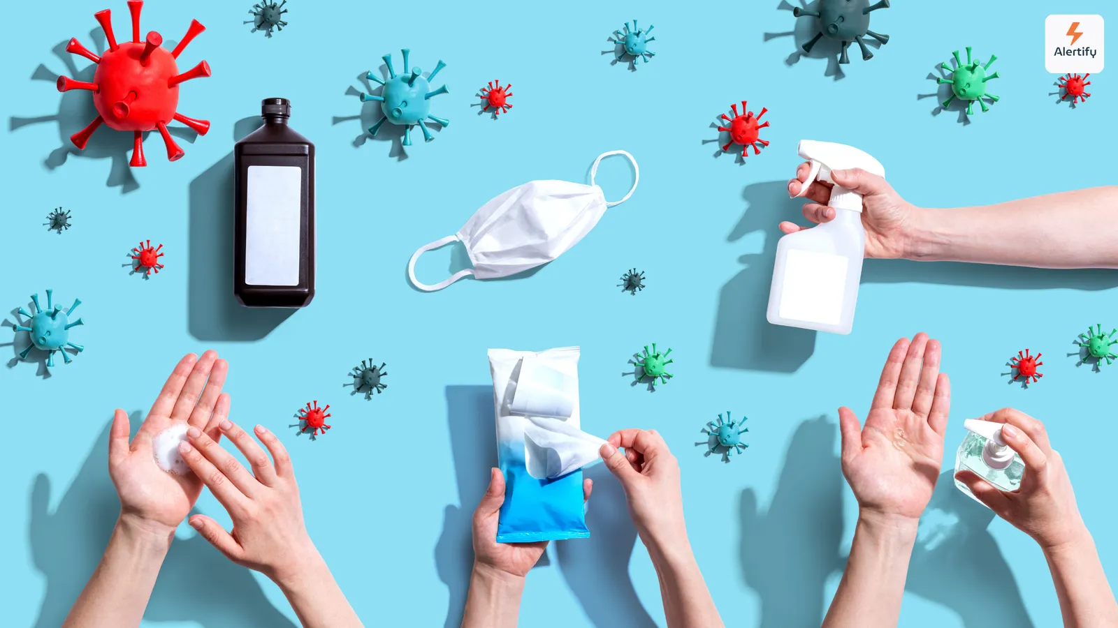 Vue de dessus de modèles de virus, d'un masque, d'un spray désinfectant et de mains utilisant des produits d'hygiène