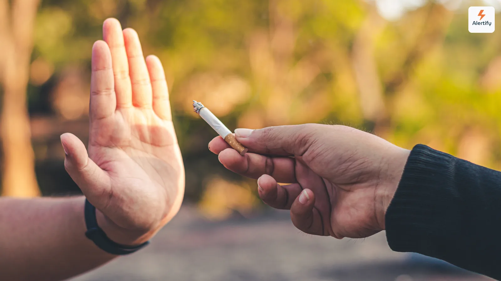 Main levée pour refuser poliment une cigarette allumée tendue par une autre personne en extérieur