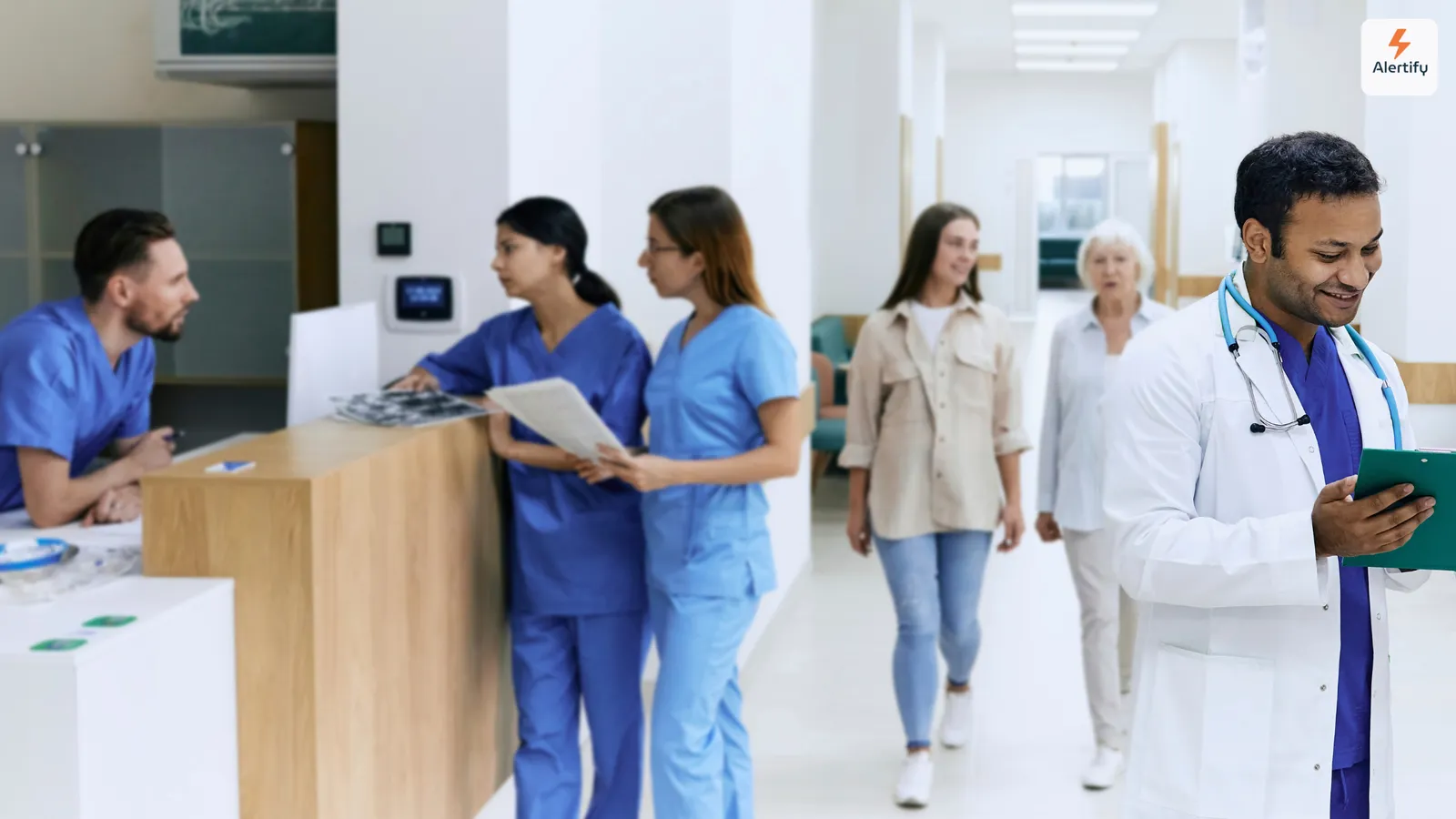 Soignants et visiteurs passant devant l'accueil dans le hall lumineux d'un hôpital