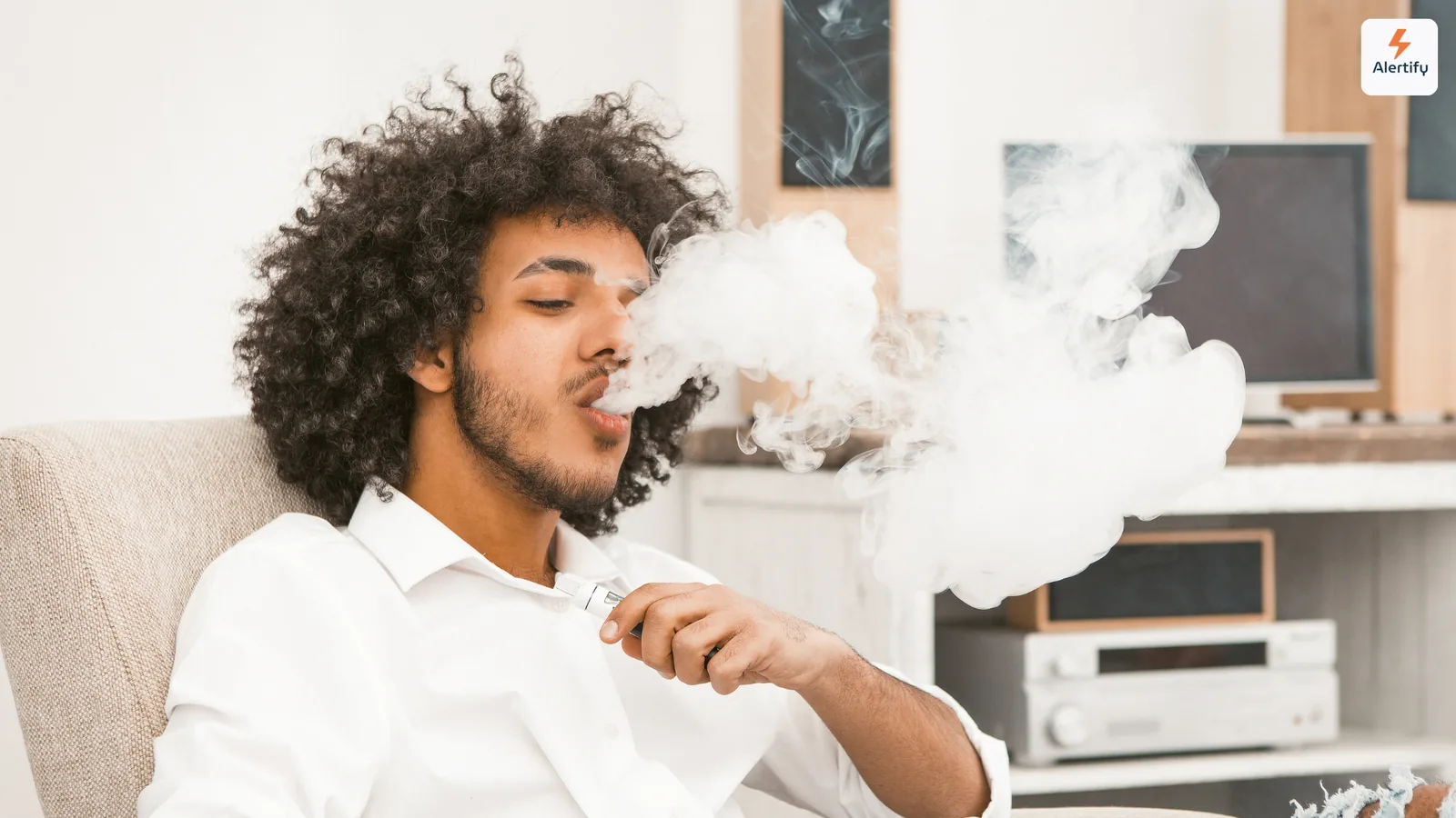 Voyageur exhalant un épais nuage de vapeur assis dans le salon d'une location de vacances